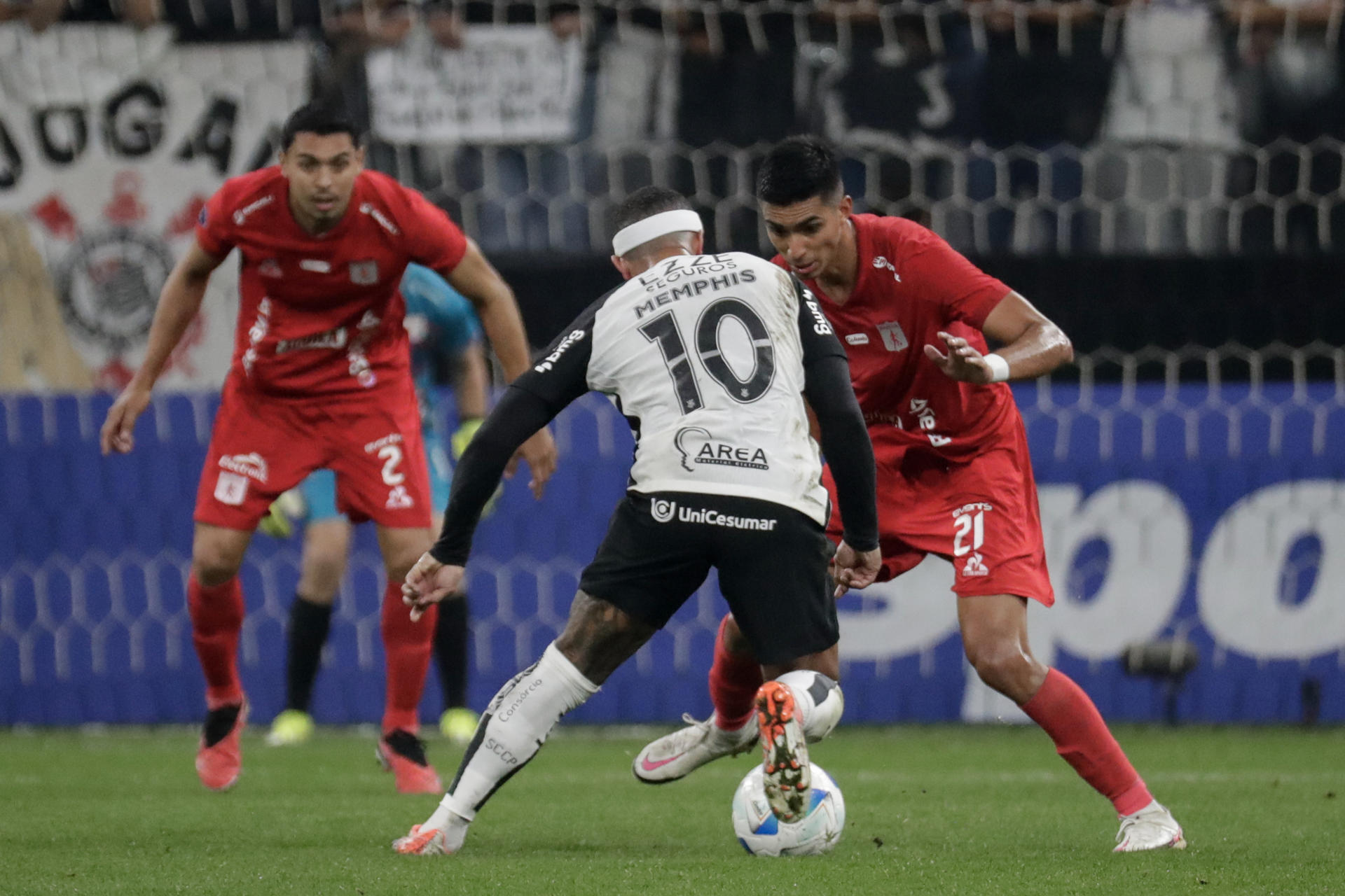 Memphis Depay (i) de Corinthians disputa un balón con Sebastián Navarro de América este martes, en un partido de la fase de grupos de la Copa Sudamericana. EFE/ Sebastiao Moreira