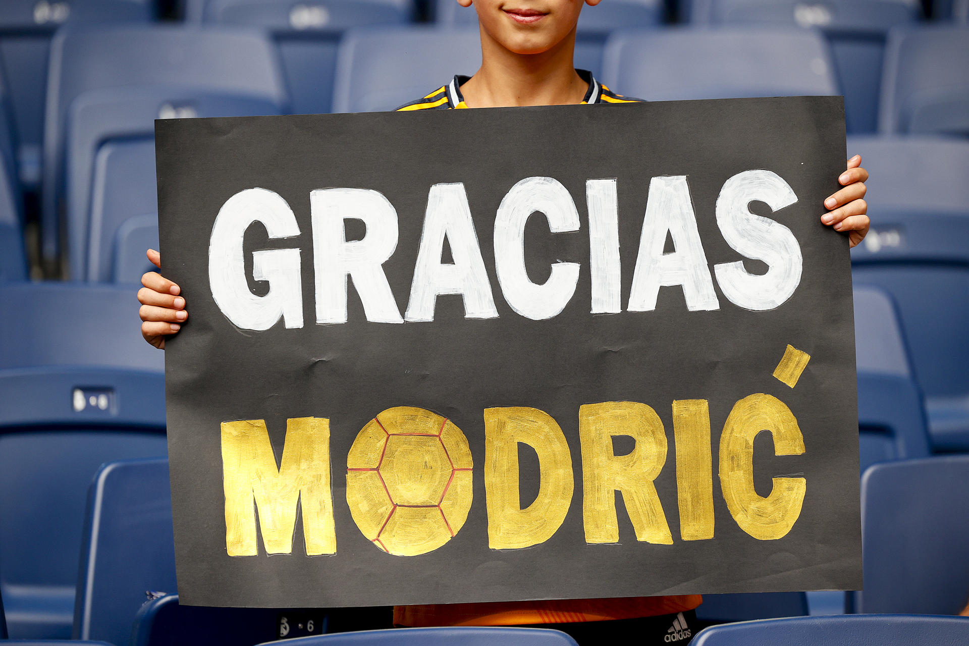 Un aficionado enseña un cartel de agradecimiento al centrocampista croata del Real Madrid Luka Modrić este sábado, previo al partido de la jornada 38 de LaLiga EA Sports, entre el Real Madrid y la Real Sociedad, celebrado en el estadio Santiago Bernabéu de la capital española. EFE/ Daniel González