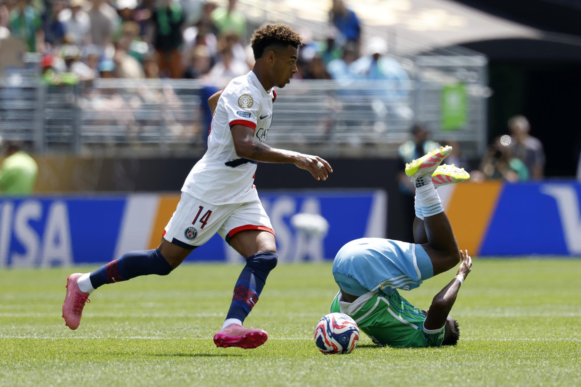 Nouhou Tolo, de los Seattle Sounders (d), cae en su intento de neutralizar el avance de Desire Doue del Paris Saint-Germain (i) este lunes en el partido de la última jornada de la fase de grupos del Mundial de Clubes jugado en Washington. EFE/EPA/JOHN G. MABANGLO