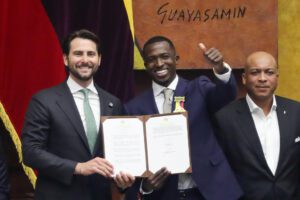El futbolista Willian Pacho (c) posa junto al presidente de la Asamblea Nacional de Ecuador, Niels Olsen (i), luego de recibir una condecoración por ser el primer ecuatoriano en ganar la Liga de Campeones. EFE/José Jácome