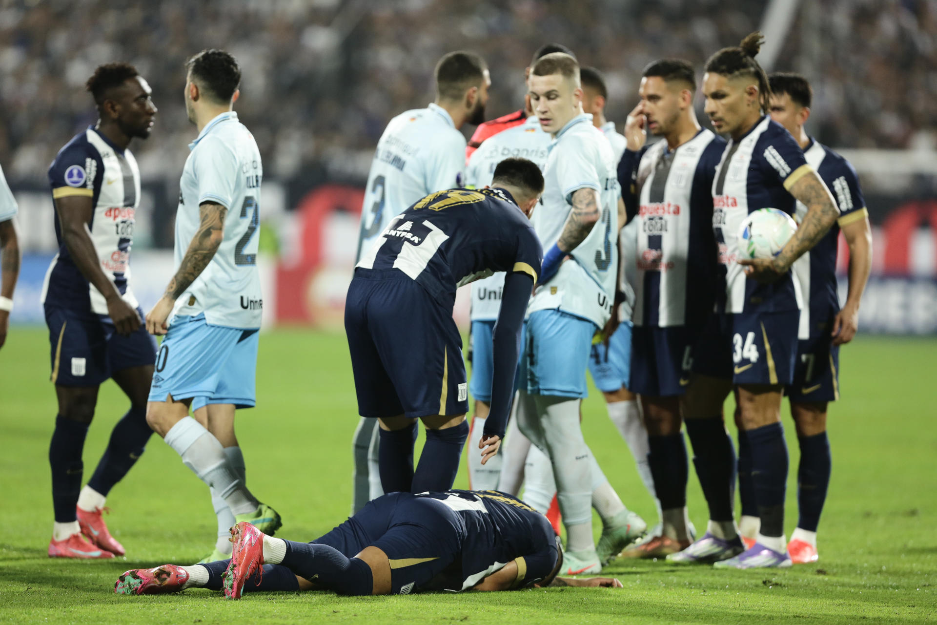 Kevin Quevedo (abajo), de Alianza Lima, yace en el césped tras recibir un golpe este miércoles, durante el partido de ida de la repesca por un cupo en los octavos de final de la Copa Sudamericana que ganó el equipo peruano por 2-0 al Gremio en el estadio Alejandro Villanueva de Lima. EFE/ John Reyes