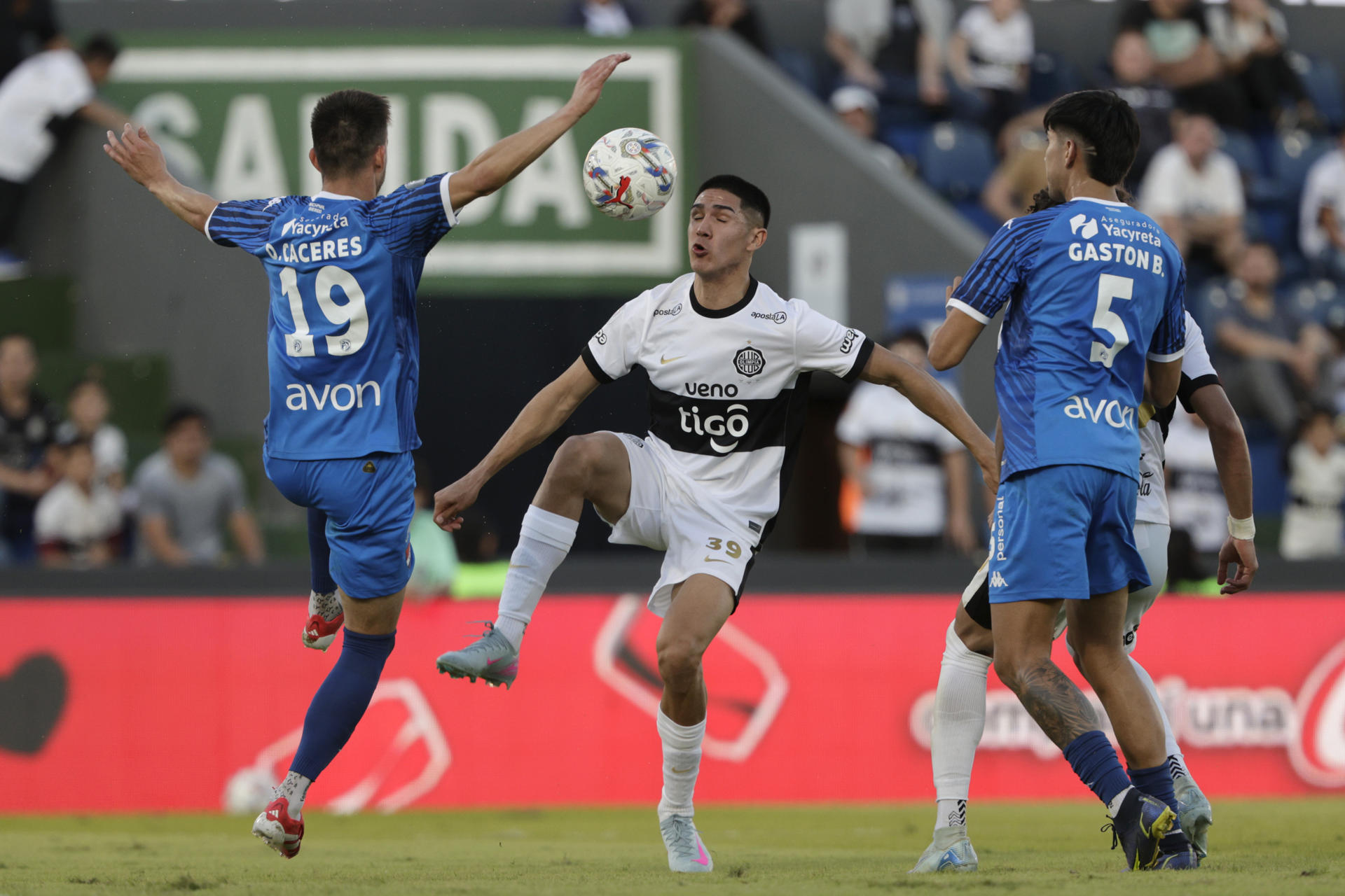 Luis Abreu (c), de Olimpia, disputa el balón con Adrián Alcaraz (i), de Nacional, en un partido del campeonato Clausura 2025 entre Olimpia y Club Nacional en el estadio Defensores del Chaco en Asunción (Paraguay). EFE/Juan Pablo Pino 