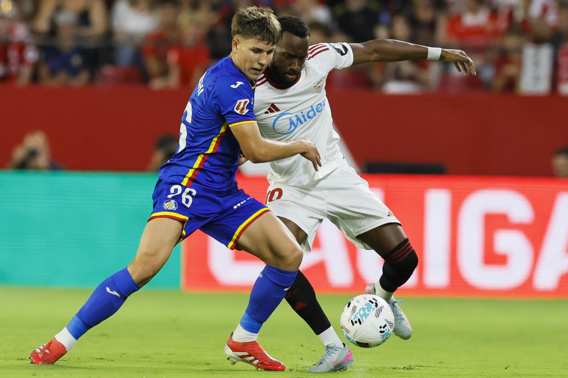 El extremo del Sevilla Dodi Lukébakio (d) ante el lateral del Getafe Davinchi durante el partido correspondiente a la segunda jornada de LaLiga EA Sports, disputado en el estadio Sánchez Pizjuán de Sevilla. EFE/José Manuel Vidal