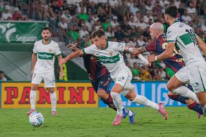 El centrocampista del Elche Germán Valera (c) pelea un balón con dos rivales del Levante durante el partido de la tercera jornada de LaLiga EA Sports en el estadio Martínez Valero. EFE/Pablo Miranzo