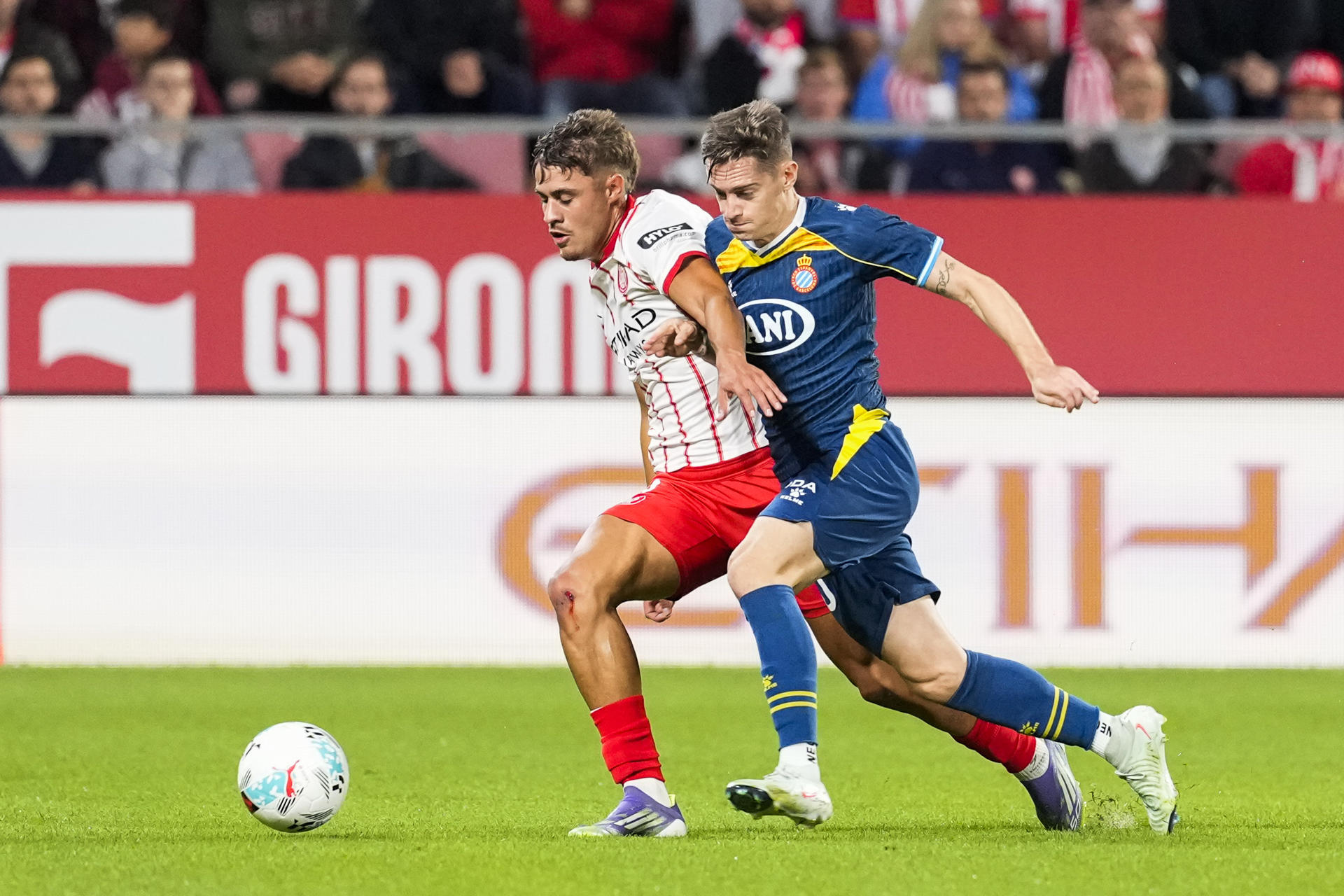 El centrocampista del Espanyol, Pol Lozano (d), disputa el balón ante el defensa del Girona, Hugo Rincón, durante el encuentro correspondiente a la jornada siete de Laliga EA Sports que disputan hoy viernes Girona y Espanyol en el estadio municipal de Montilivi, en Girona. EFE/David Borrat. 