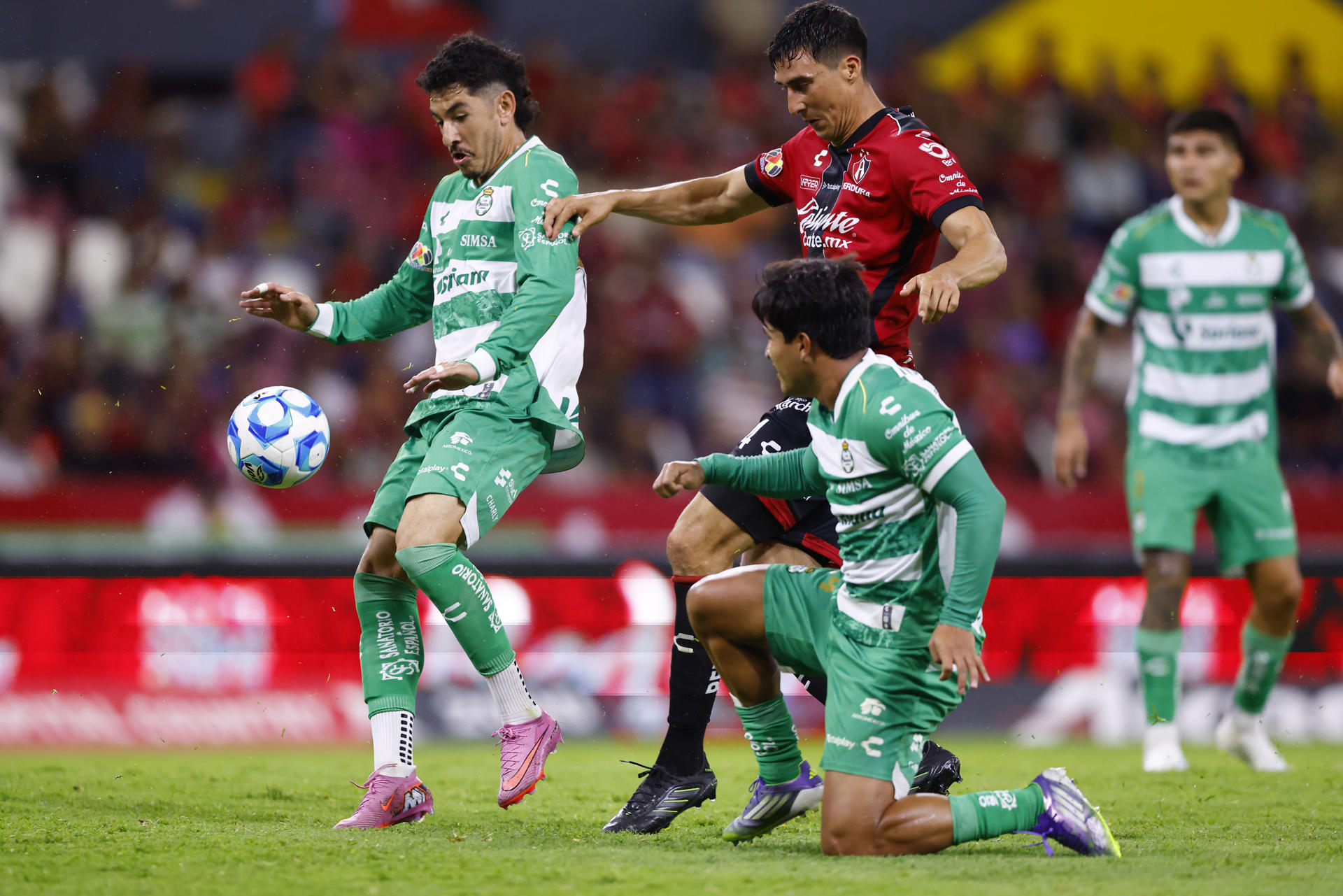 Adrián Mora (c) de Atlas disputa el balón con Jesús Ocejo (i) y Diego Medina de Santos durante un partido del Torneo Apertura 2025 de la Liga MX en Guadalajara (México). EFE/ Francisco Guasco 