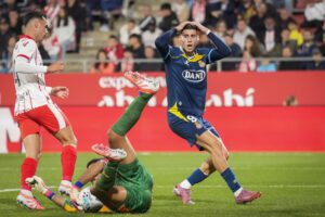 El guardameta argentino del Girona, Paulo Gazzaniga (c), captura el balón ante el delantero del Espanyol, Roberto Fernández, durante el encuentro correspondiente a la jornada siete de Laliga EA Sports que disputan hoy viernes Girona y Espanyol en el estadio municipal de Montilivi, en Girona. EFE/David Borrat.