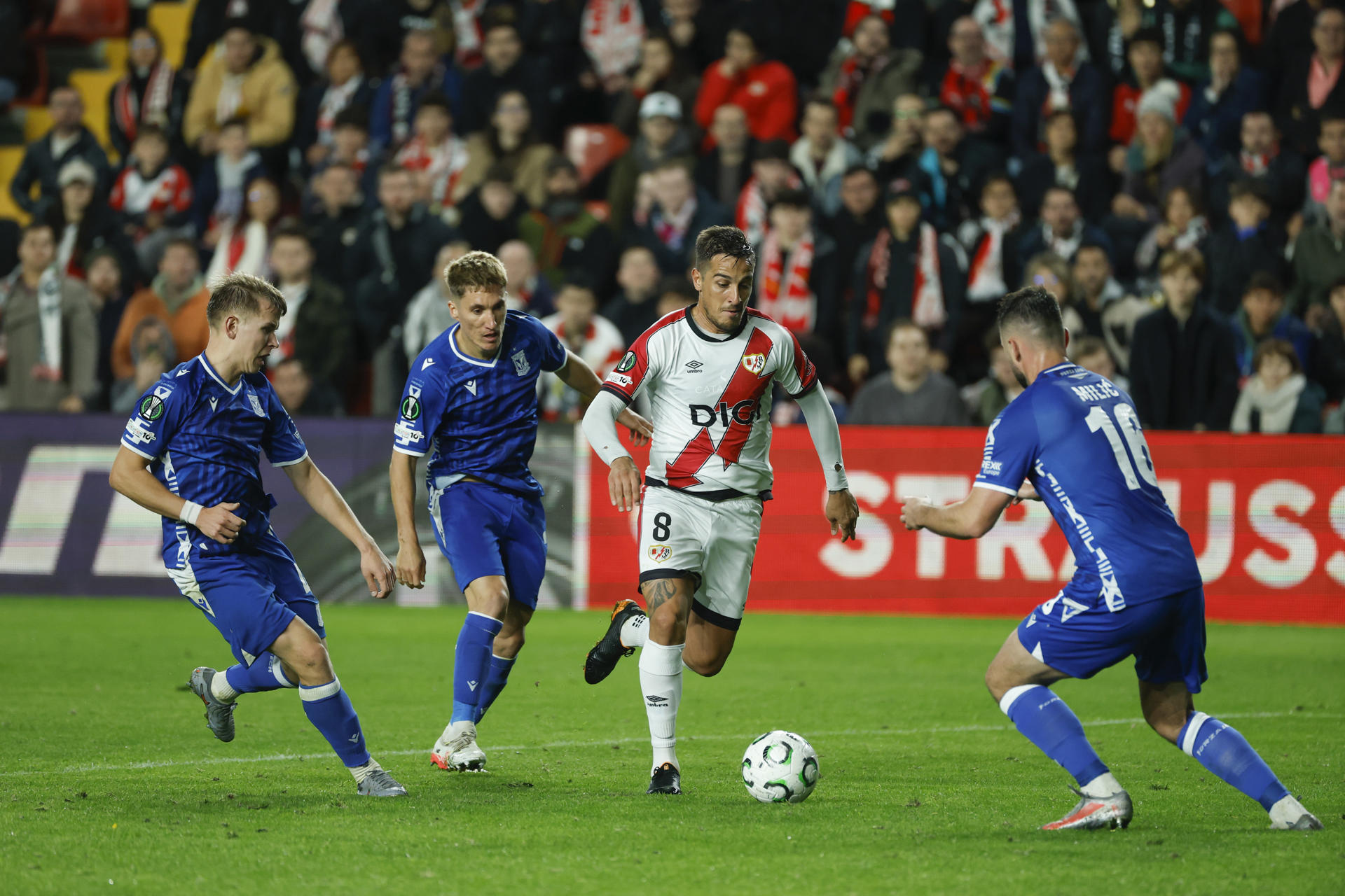 El centrocampista del Rayo Óscar Trejo (2-d) juega un balón entre varios jugadores del Lech Poznan, durante el partido de la Liga Conferencia que Rayo Vallecano y Lech Poznan disputan este jueves en el estadio de Vallecas, en Madrid. EFE/Juanjo Martín 