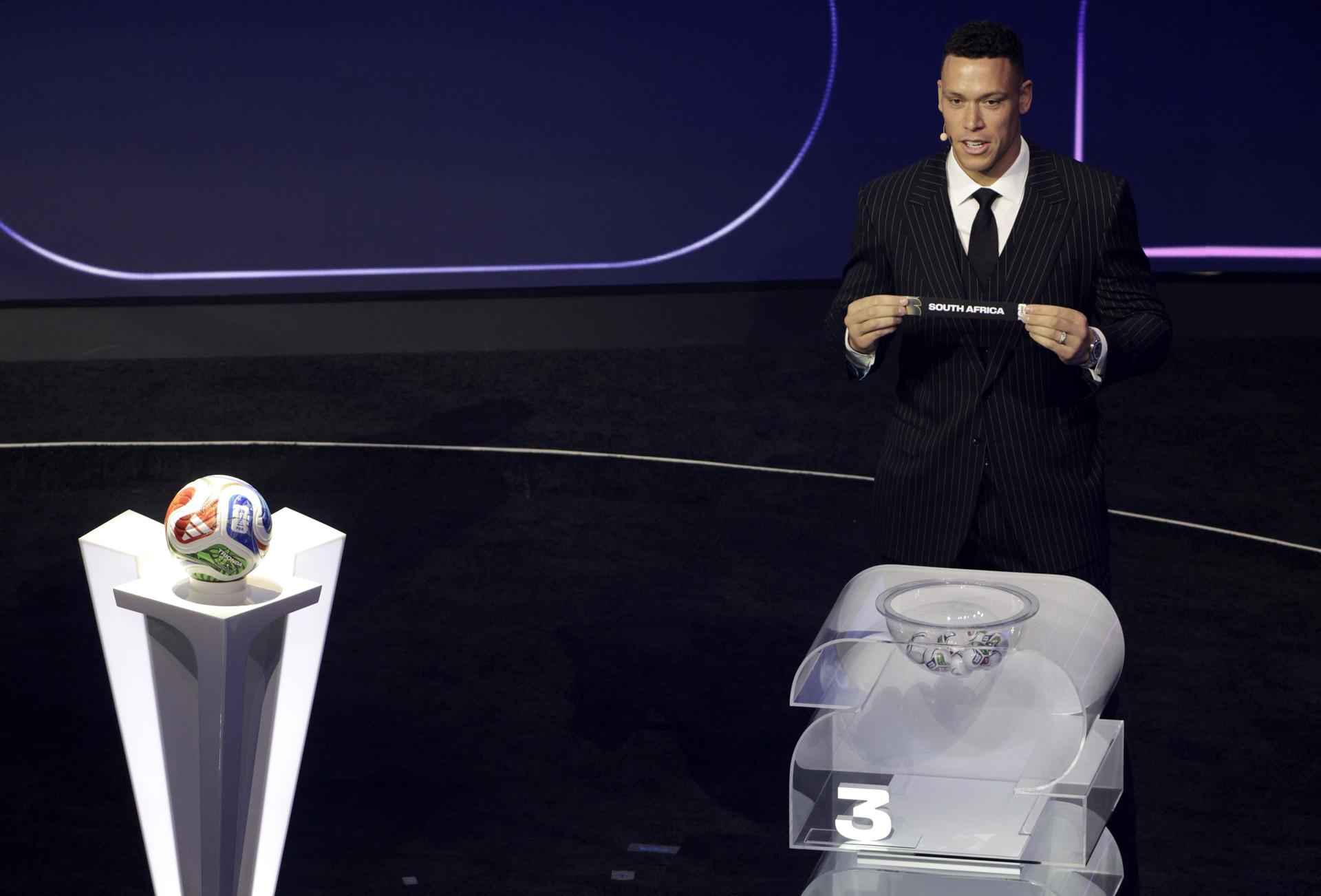 Aaron Judge sostiene el boleto de Sudáfrica durante el sorteo final de la Copa Mundial de la FIFA 2026. EFE/EPA/Shawn Thew 