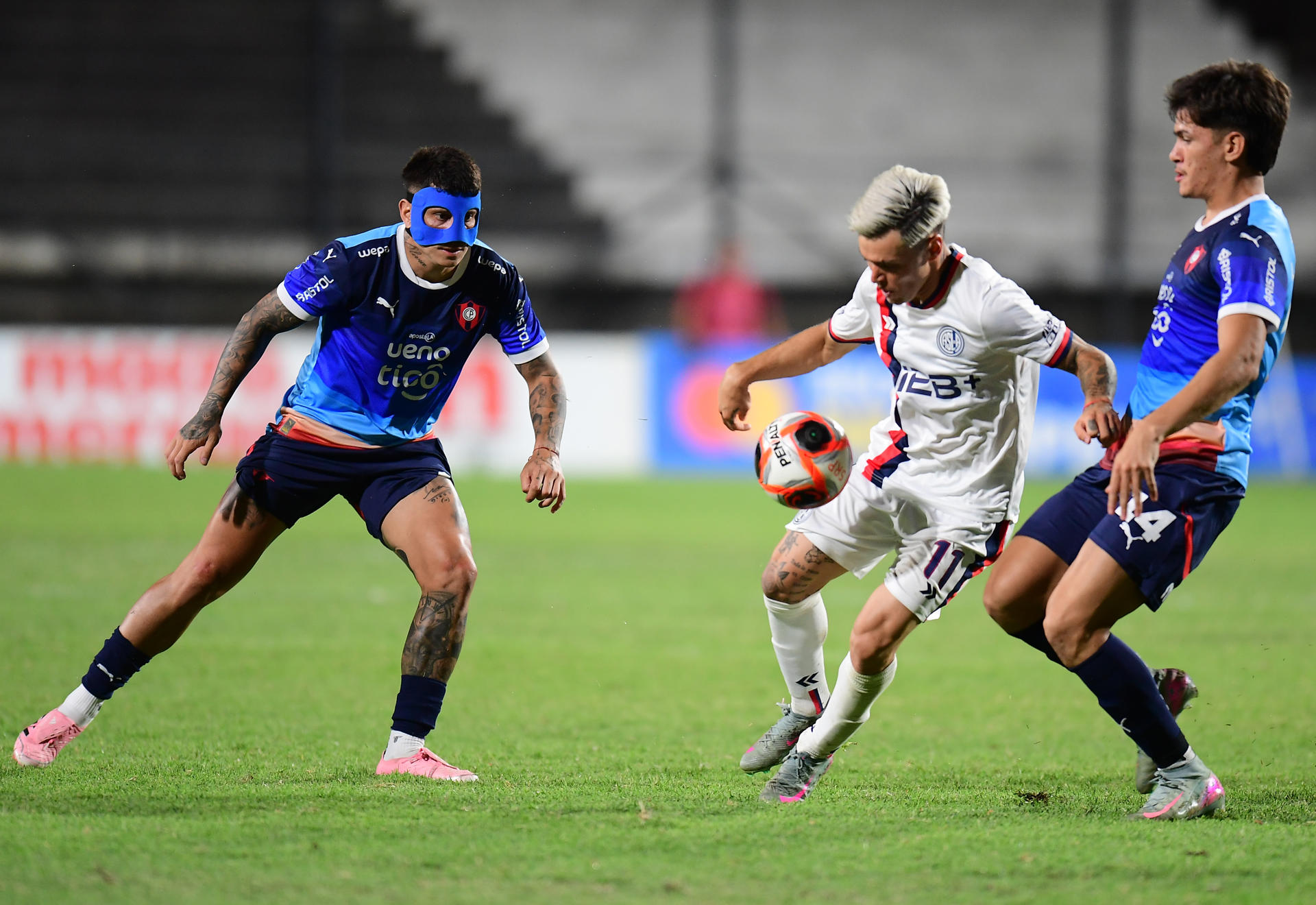 El creativo de San Lorenzo Matías Reali (c) busca salir de la marca de los defensores de Cerro Porteño Lucas Quintana (d) y Juan Manuel Iturbe (i) durante el partido amistoso jugado este sábado en en el estadio Parque Viera de Montevideo. EFE/ STR 