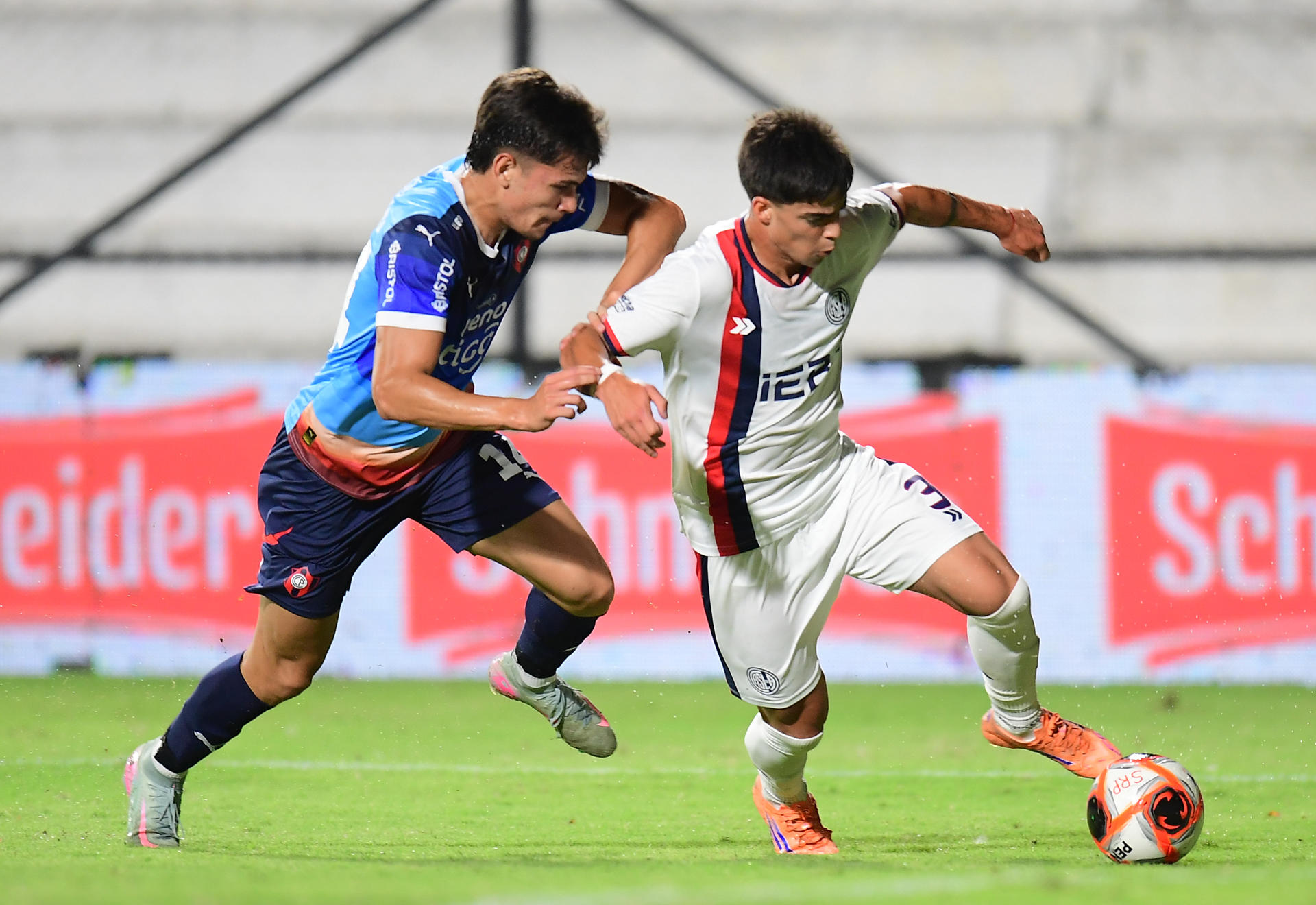 El extremo de San Lorenzo Teo Rodríguez (d) avanza con el balón ante la presión del defensor de Cerro Porteño Lucas Quintana en el partido amistoso jugado este sábado en el estadio Parque Viera de Montevideo. EFE/ STR 