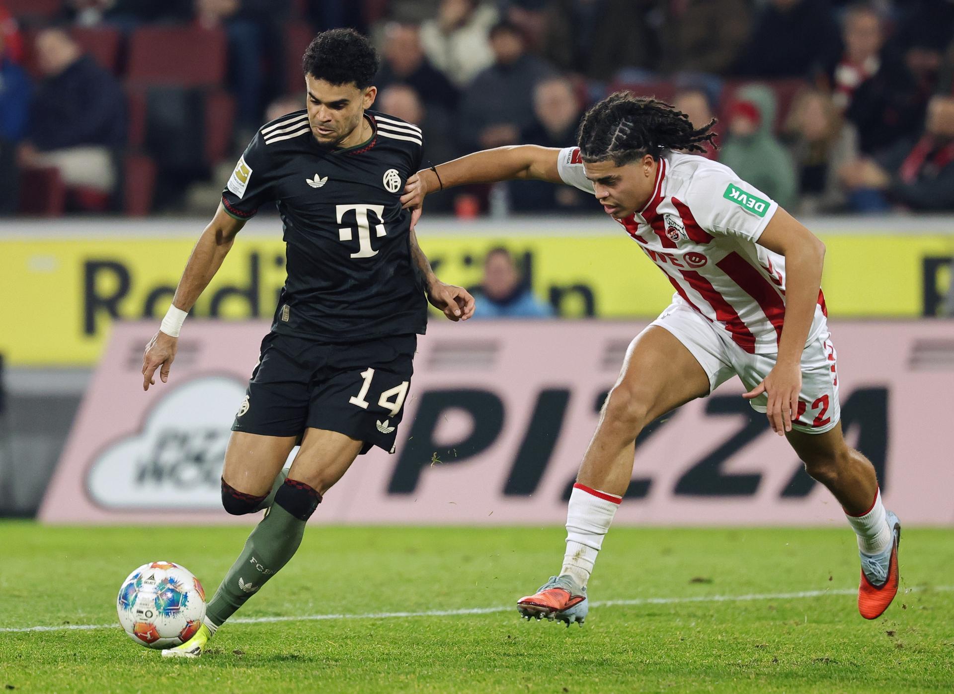 El colombiano Luis Díaz (i), del Bayern Múnich, y Jahmai Simpson-Pusey (d), del Colonia, en acción durante el partido disputado este miércoles, correspondiente a la Bundesliga. EFE/FRIEDEMANN VOGEL 