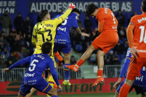 El defensa de la Real Sociedad, Jon Aramburu (d), remata ante la salida en falso del guardameta del Getafe, David Soria, en la jugada que ha significado el segundo gol del equipo donostiarra durante el partido de la jornada 19 de LaLiga EA Sports que disputaron Getafe CF y la Real Sociedad este viernes en el Coliseum de Getafe. EFE/ Juanjo Martín