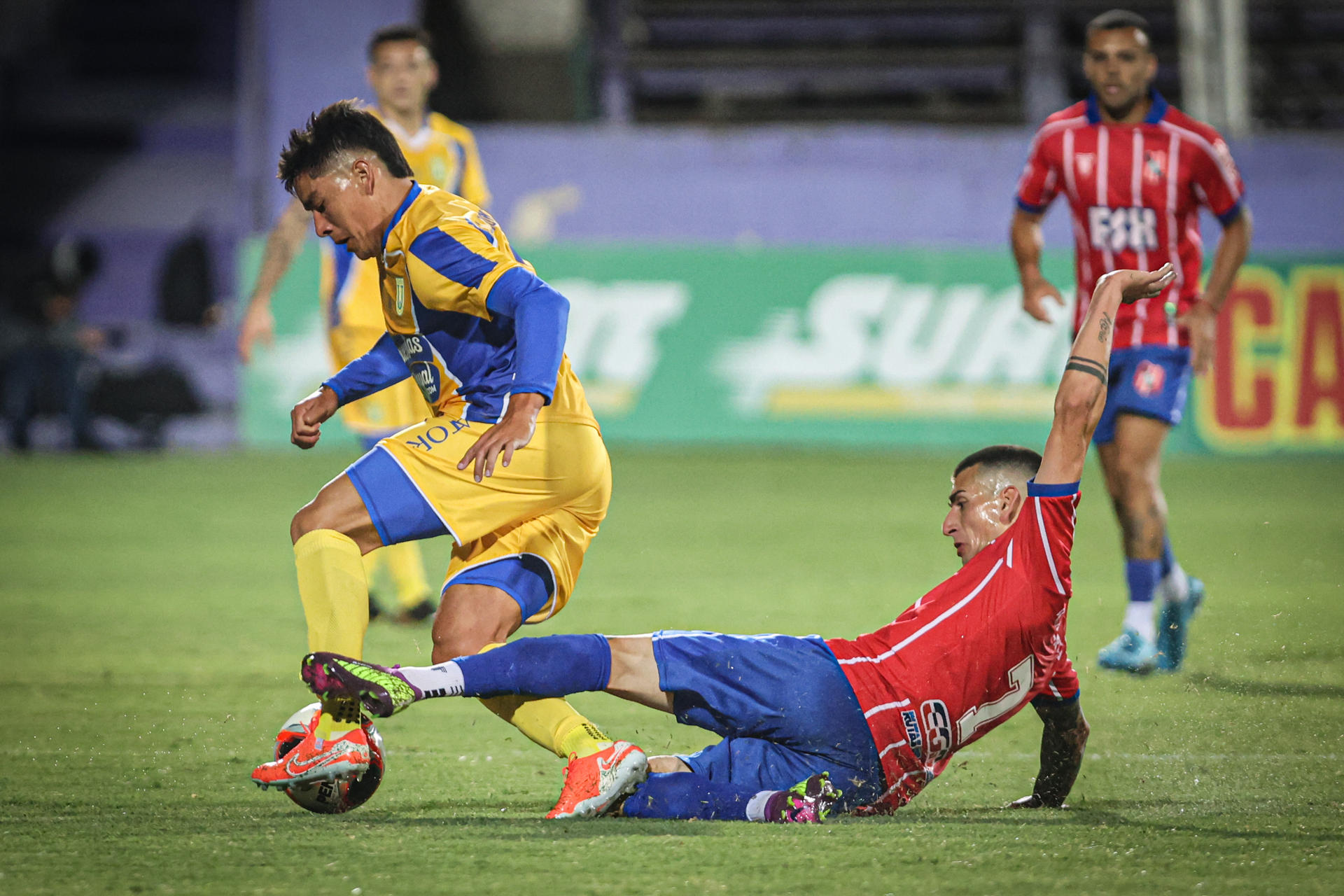 Franco Muñoz (d), del club uruguayo Central Español, se arroja sin éxito en pos del balón con el que avanza el extremo de Universidad de Concepción Leonel González este lunes, en un partido de pretemporada jugado en el estadio Luis Franzini de Montevideo. EFE/ Gastón Britos 