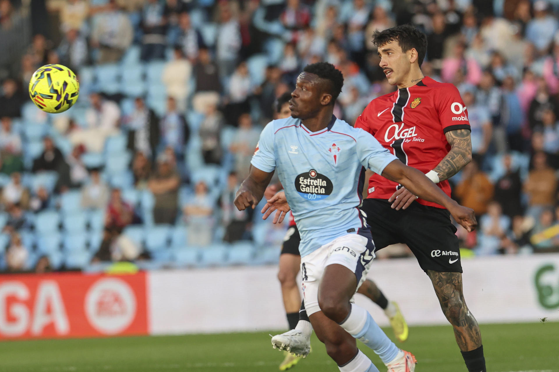 El defensa del Celta Joseph Aidoo (i) pelea un balón ante el centrocampista del Mallorca Antonio Sánchez durante el partido de la jornada 25 de LaLiga EA Sports que Celta de Vigo y RCD Mallorca disputan, en el Estadio de Balaidos. EFE/ Salvador Sas