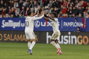 El delantero brasileño del Real Madrid Vinícius Júnior (d) celebra con su compañero, el francés Kylian Mbappé, tras anotar el gol del empate durante el partido de la jornada 25 de LaLiga que disputaron CA Osasuna y Real Madrid en el estadio de El Sadar de Pamplona. EFE/ Villar López