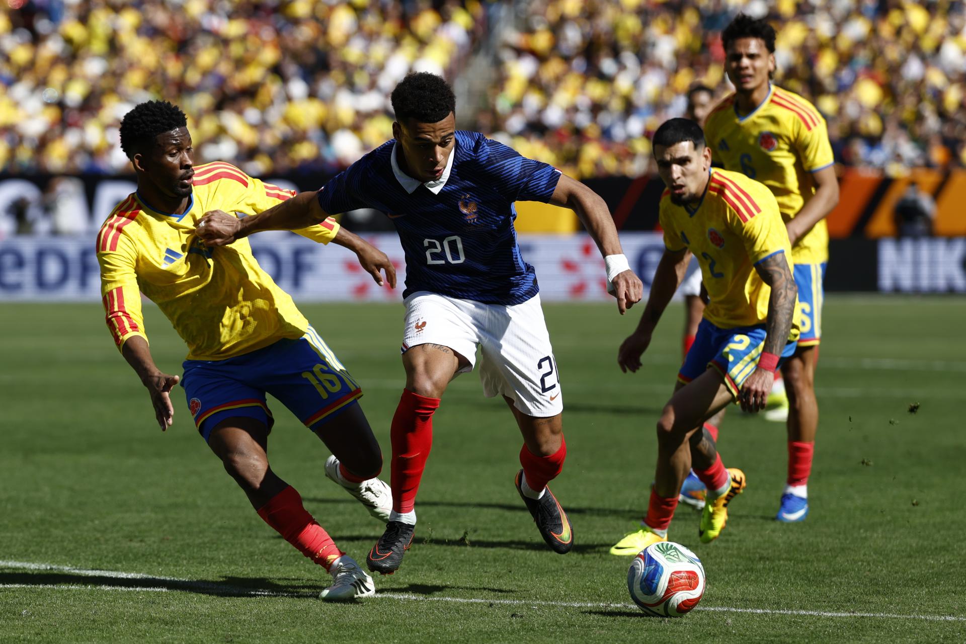 El francés Désiré Doué (C) en acción entre Jefferson Lerma (I) y Daniel Muñoz (D), de Colombia, durante el partido amistoso en Landover, Maryland, EE.UU. EFE/EPA/WILL OLIVER