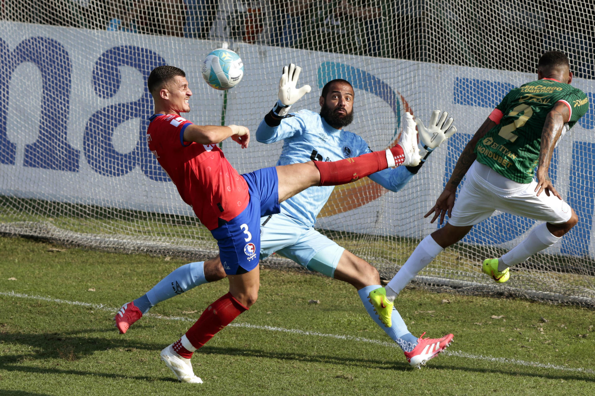 Henry Figueroa (d), de Marathón, disputa el balón con Facundo Queiroz (i) y Edrick Menjivar, de Olimpia, en un partido de la Liga Nacional de Honduras entre Marathón y Olimpia en el estadio Yankel Rosenthal en San Pedro Sula (Honduras). EFE/José Valle
