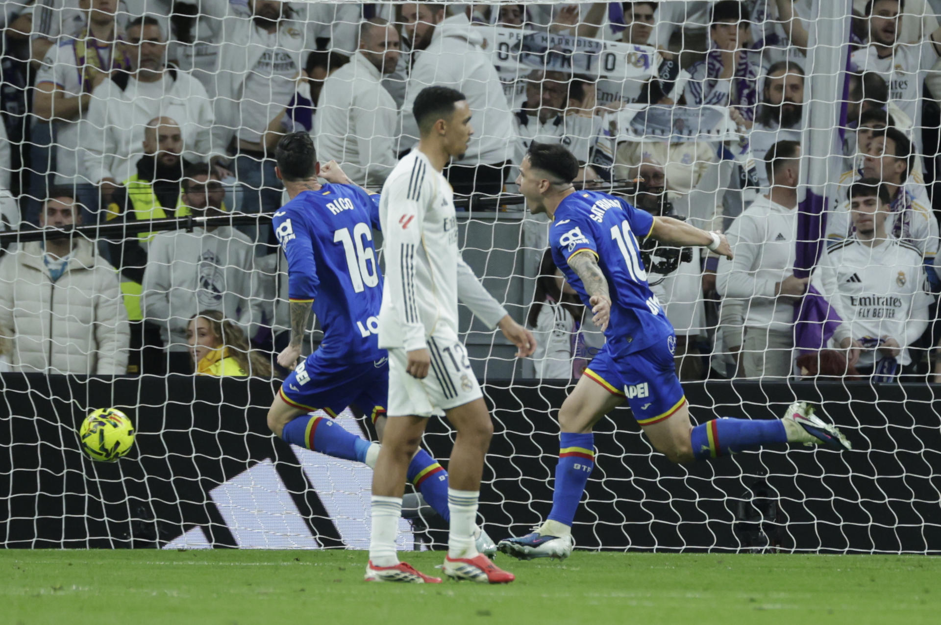 El delantero del Getafe Martín Satriano (d) celebra tras marcar el 0-1, durante el partido de LaLiga de fútbol que Real Madrid y Getafe CF disputan en el estadio Santiago Bernabéu. EFE/Juanjo Martín

