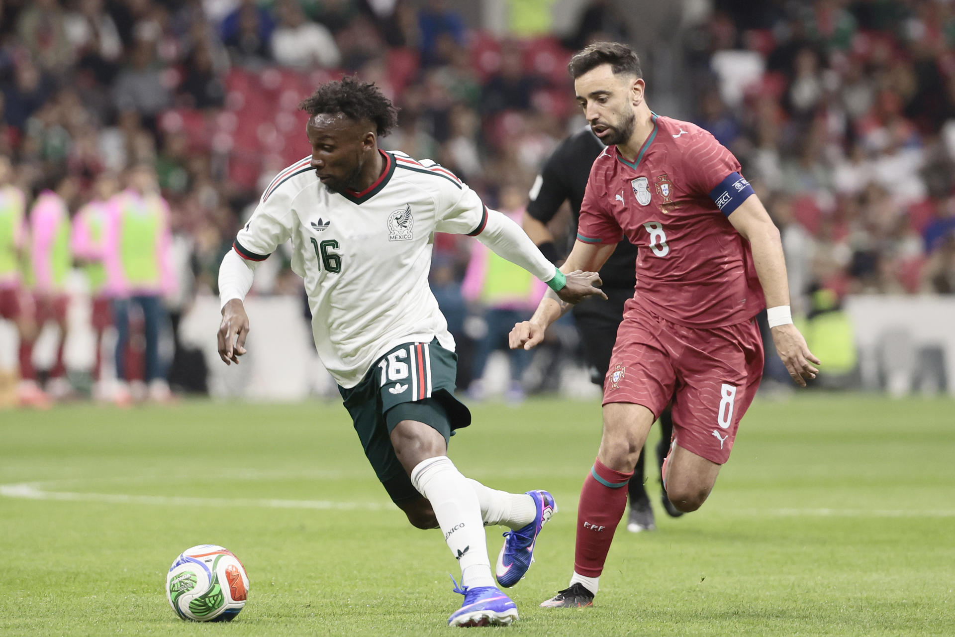 Julián Quiñones (i), de México, avanza ante la marca del portugués Bruno Fernandes en el juego amistoso en el remodelado estadio Azteca, que se denomina ahora estadio Banorte, en Ciudad de México. EFE/José Méndez