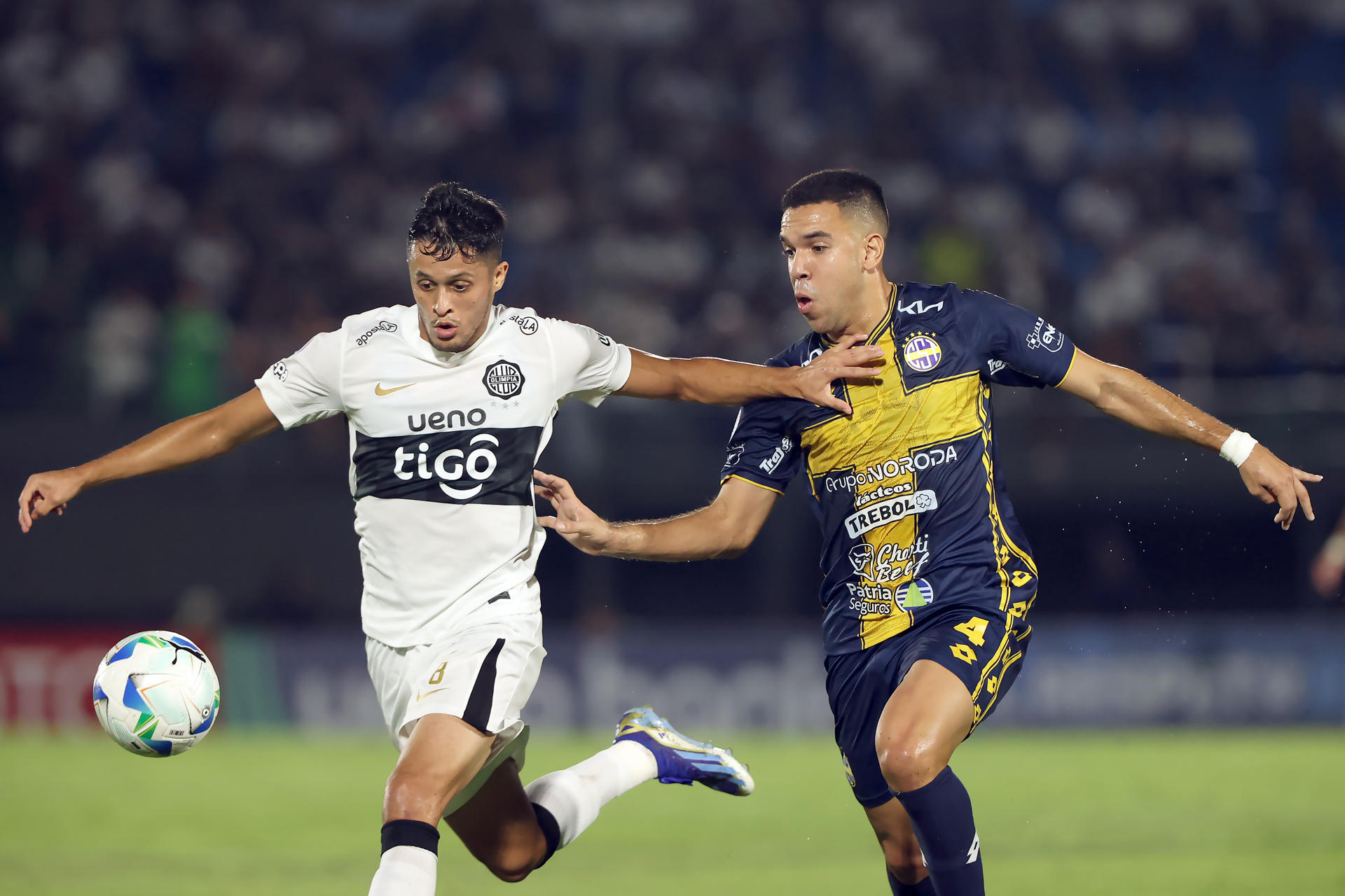 Alex Franco (i), de Olimpia, avanza ante la marca de Diego Melgarejo, de Sportivo Trinidense. EFE/Juan Pablo Pino