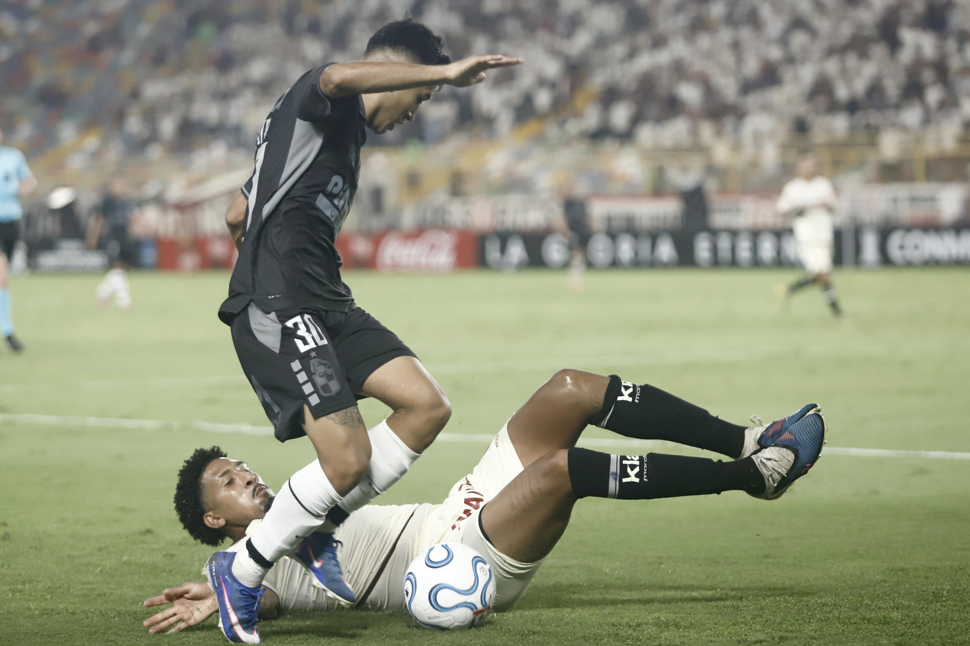 El defensor de Universitario de Deportes Jesús Castillo cae al intentar neutralizar el avance de Benjamín Chandía de Coquimbo Unido este martes en partido de la segunda jornada de la fase de grupos de la Copa Libertadores jugado en el estadio Monumental de Lima. EFE/ Sebastián Blanco 