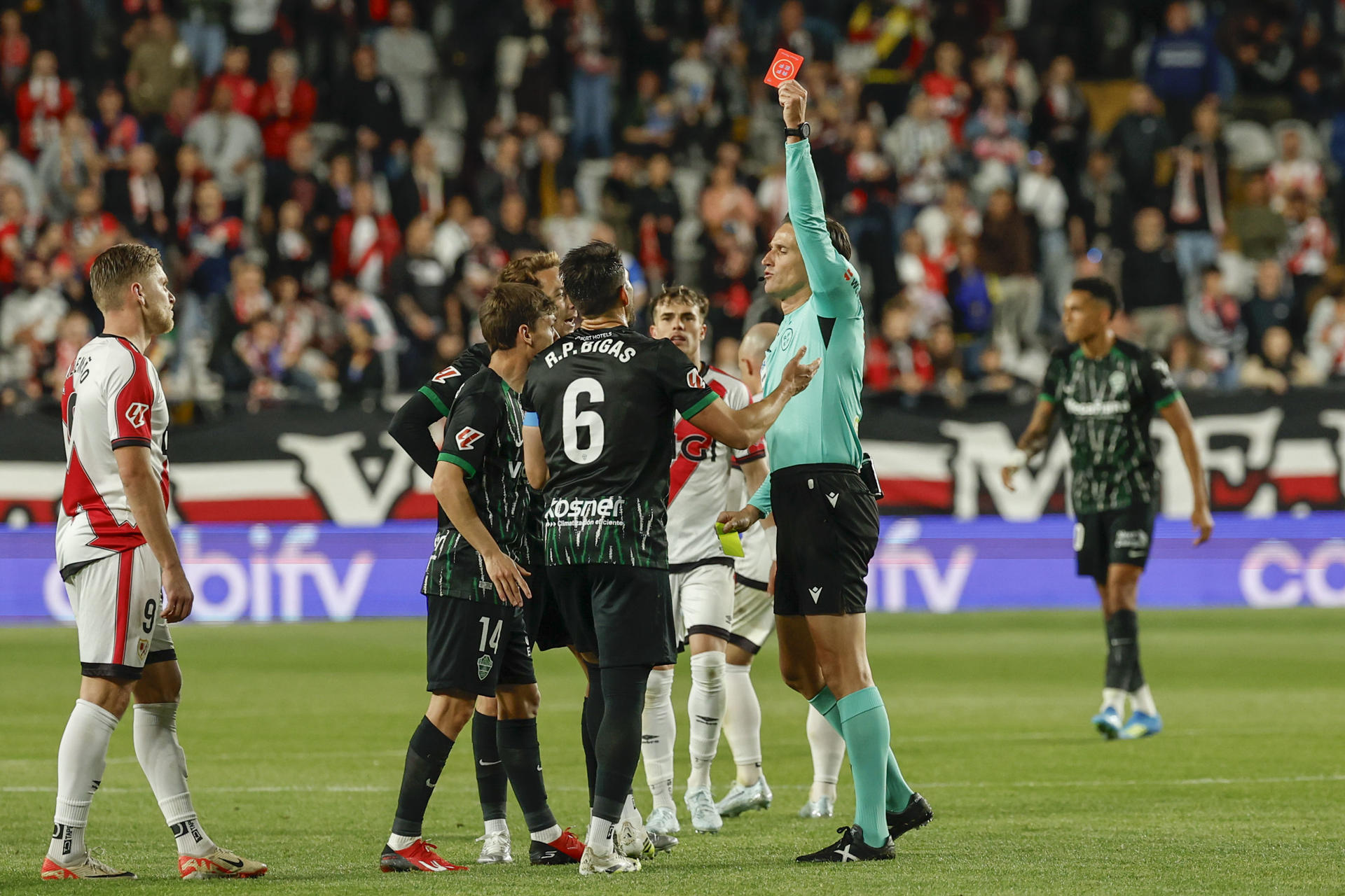 El defensa del Elche Pedro Bigas (c) recibe tarjeta roja durante el partido de la jornada 30 de LaLiga EA Sports que Rayo Vallecano y Elche CF disputan este viernes en el estadio de Vallecas, en Madrid. EFE/ Mariscal