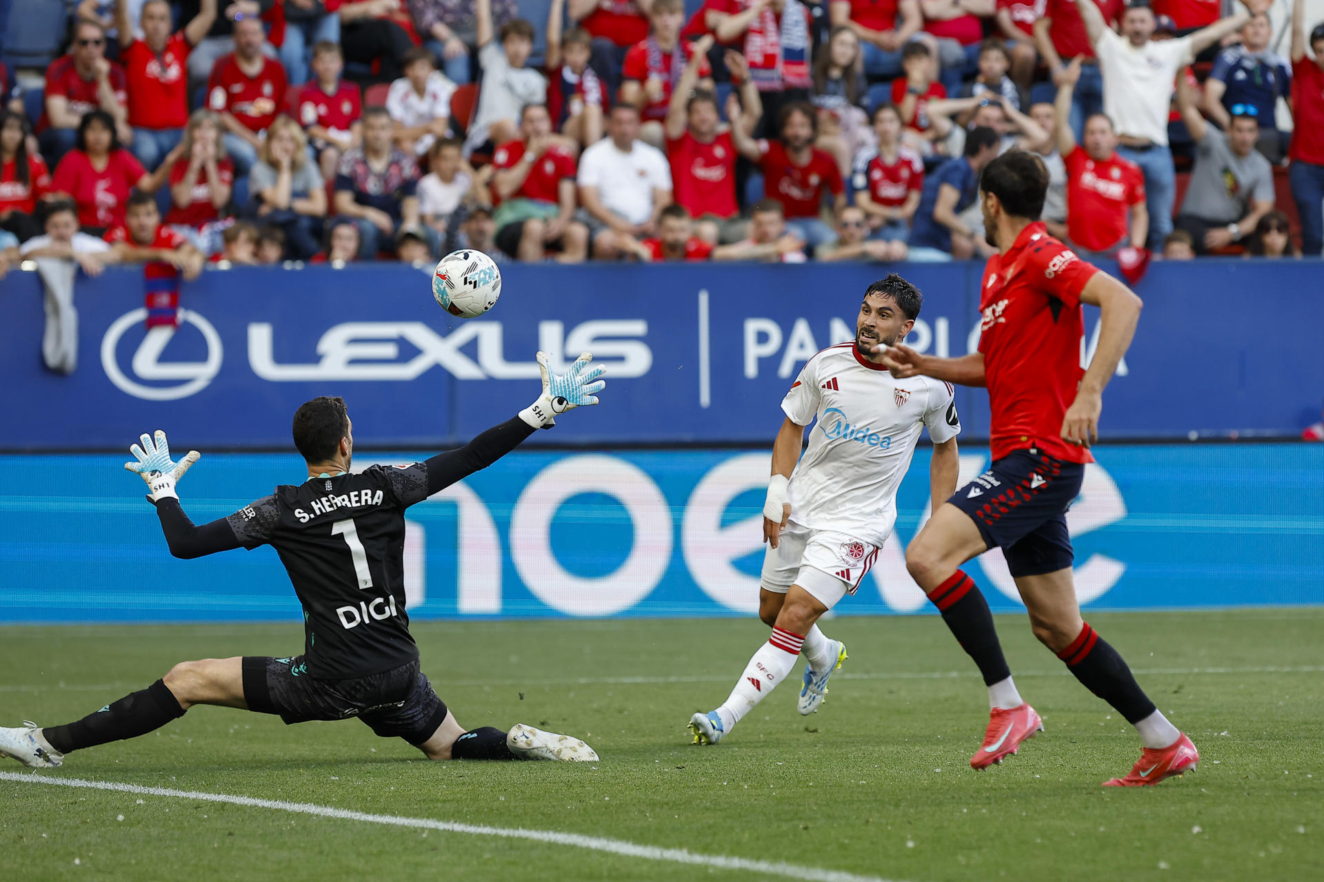 El cdelantero francés del Sevilla Neal Maupay (c) dispara a puerta ante Sergio Herrera (i), guardameta de Osasuna, durante el partido de la jornada 32 de LaLiga que Atlético Osasuna y Sevilla FC disputan este domingo en el estadio de El Sadar, en Pamplona. EFE/ Villar López 