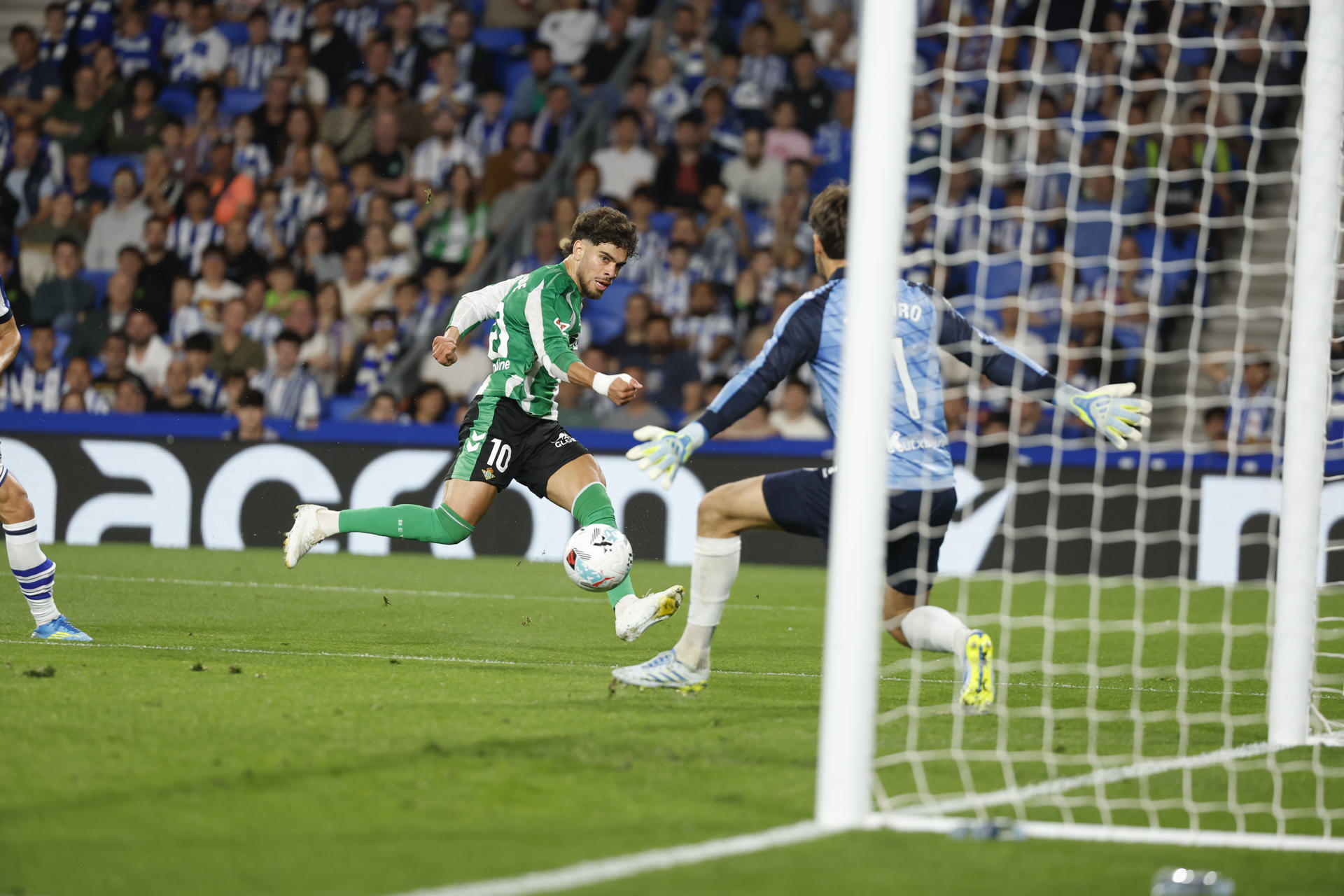 El delantero marroquí del Betis, Abde Ezzalzouli (i), remata ante el guardameta de la Real Sociedad, Alex Remiro, durante el encuentro correspondiente a la jornada 35 de Laliga EA Sports que disputaron Real Sociedad y Betis en el estadio de Anoeta, en San Sebastián. EFE / Juan Herrero. 