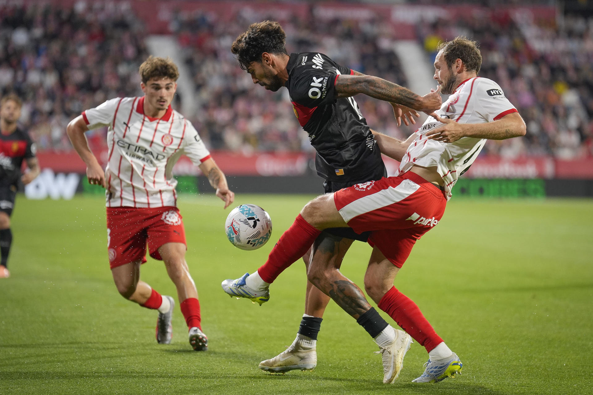 El centrocampista portugués del Mallorca Samu Costa (2d) pelea un balón con el defensa neerlandés del Girona Daley Blind (d) durante el partido de La Liga de fútbol entre el Girona FC y RCD Mallorca, este viernes en el estadio municipal de Montilivi. EFE/David Borrat.

