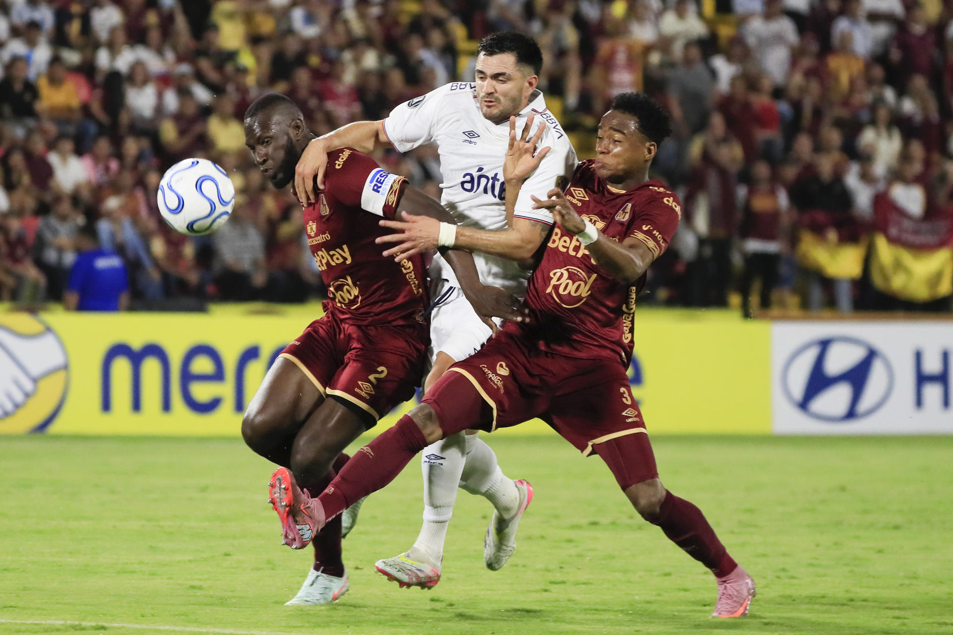 Anderson Angulo (i) y Jan Carlos Angulo (d), del Tolima, disputan el balón con Maximiliano Gómez, del Nacional, en el estadio Manuel Murillo Toro de Ibagué. EFE/Carlos Ortega
