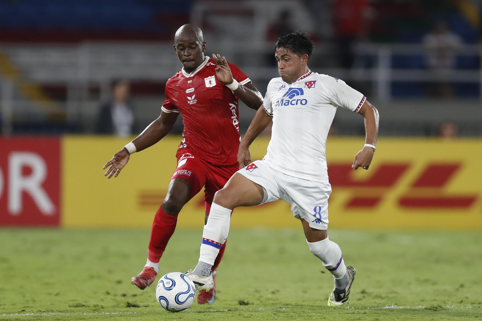 Tilman Palacios (i), de América, disputa el balón con Martín Garay, de Tigre, en un partido de la fase de grupos de la Copa Sudamericana en el estadio Pascual Guerrero en Cali (Colombia). EFE/Ernesto Guzmán
