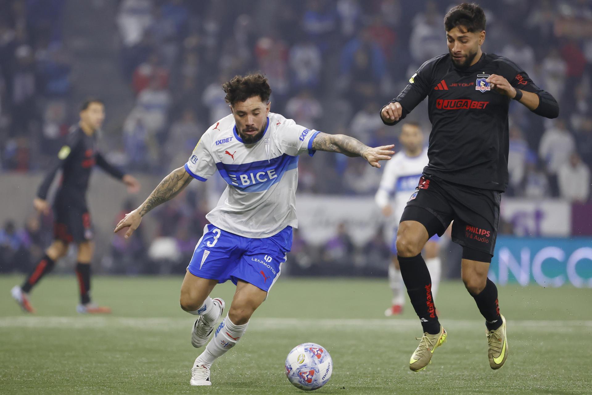 Eugenio Mena (i), de Universidad Católica, disputa un balón con Jeyson Rojas, de Colo-Colo, en un partido de la Liga de Primera entre Universidad Católica y Colo-Colo en el estadio Claro Arena en Santiago (Chile). EFE/Elvis González