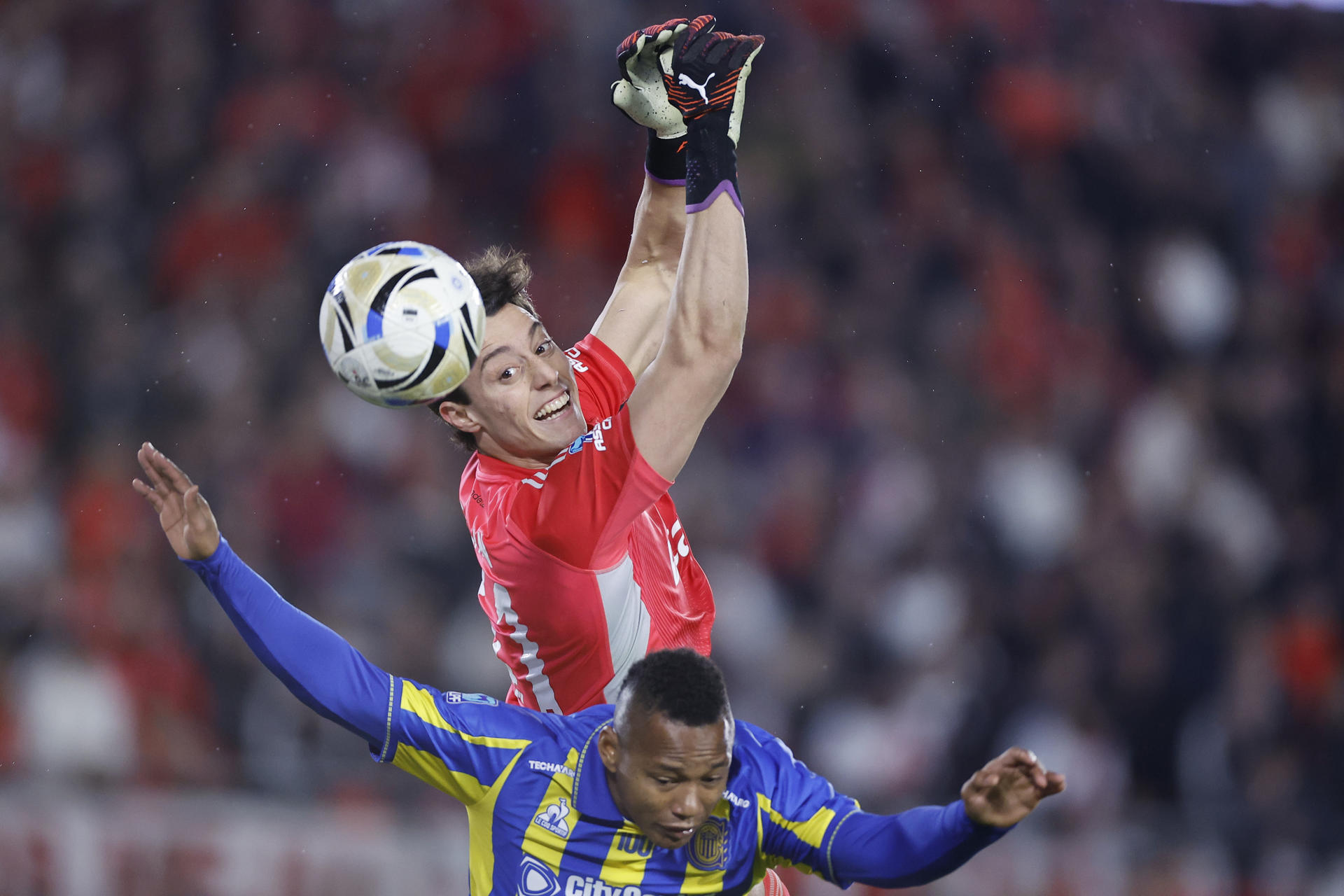 El guardameta de River Plate Santiago Beltrán (arriba) pierde el control del balón durante un duelo con el delantero colombiano de Rosario Central, Jáminton Campaz, este sábado durante el partido de semifinales del Torneo Apertura argentino jugado en el estadio Monumental de Buenos Aires. EFE/ Juan Ignacio Roncoroni
