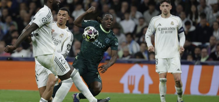 El delantero belga del Manchester City Jeremy Doku (d) disputa el balón ante los jugadores del Real Madrid, el alemán Antonio Rudiger y el británico Trent Alexander-Arnold, durante el encuentro correspondiente a la ida de los octavos de final de la Liga de Campeones que Real Madrid y Manchester City disputaron en el estadio Santiago Bernabéu, en Madrid. EFE/Kiko Huesca