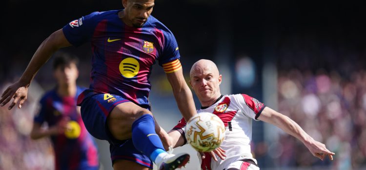 El jugador del FC Barcelona Ronald Araujo (i) lucha por el balón con Isi (d), del Rayo Vallecano, durante su partido de la jornada 29 de LaLiga EA Sports en el Camp Nou, este domingo. EFE/ Alejandro Garcia