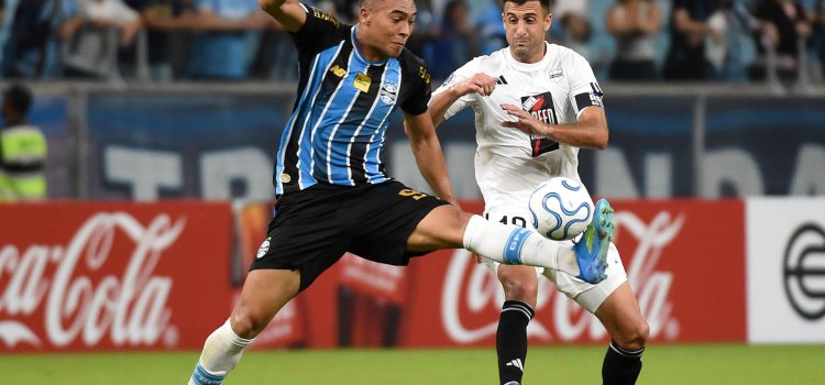 Carlos Vinícius (i), de Gremio, domina el balón por delante de Juan Randazzo, de Deportivo Riestra, este martes durante un partido de la Copa Sudamericana en el estadio Arena do Gremio, en Porto Alegre (Brasil). EFE/ Ricardo Rimoli