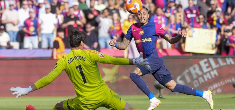 El delantero del Barcelona Raphinha, y el portero del Real Madrid Thibaut Courtois, durante el partido de la jornada 35 de LaLiga EA Sports entre el Barcelona y el Real Madrid, este domingo en el Estadi Olímpic Lluís Companys.-EFE/ Siu Wu