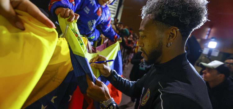 El jugador José Martínez firma una bandera durante el recibimiento a la selección de Venezuela frente al Hotel Hilton Garden en Montevideo. EFE/ Gastón Britos