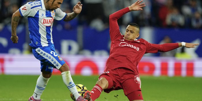 El centrocampista británico del Espanyol Tyrhys Dolan (i) pelea un balón con el chileno Alexis Sánchez, del Sevilla, durante el partido de la jornada 13 de LaLiga EA Sports entre el RCD Espanyol y el Sevilla FC, este lunes en el RCDE Stadium. EFE/ Alejandro Garcia